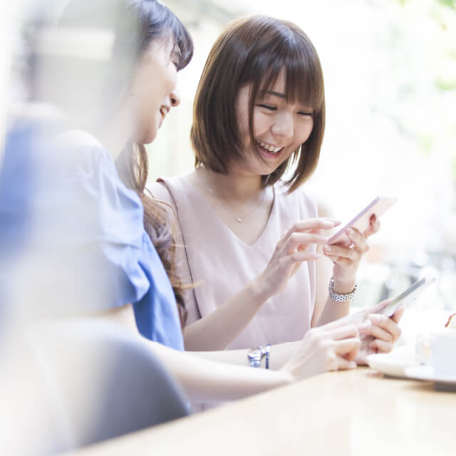 画像：スマートフォンを利用する女性2人